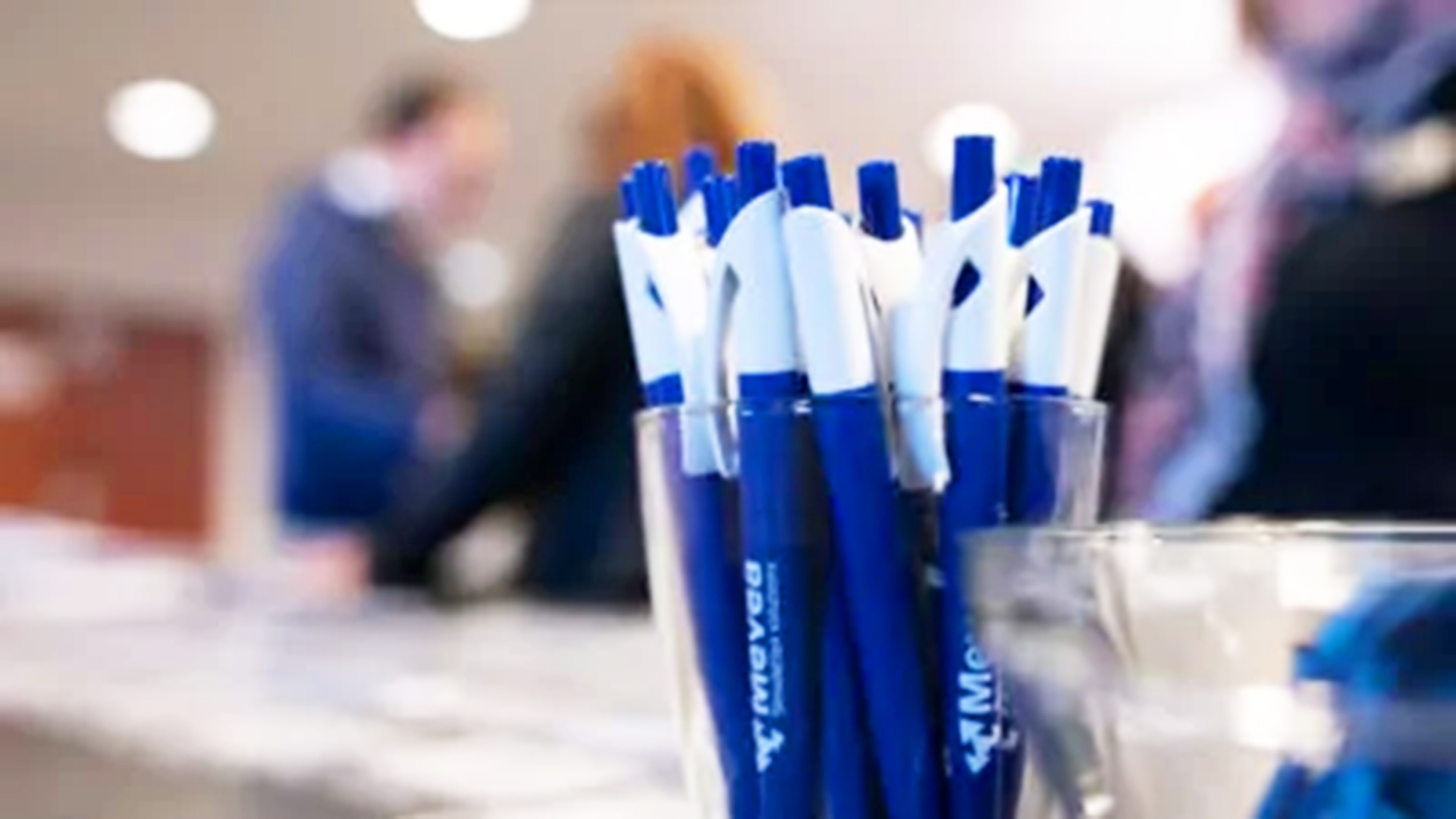 Mevea pens on a table and people on the background.